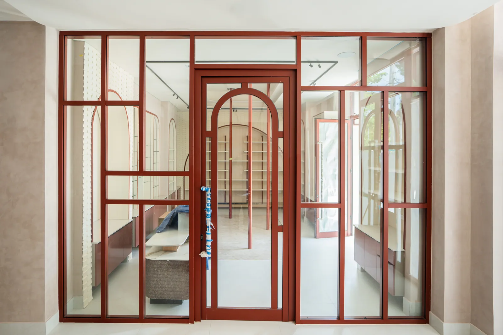 Acceso acristalado con perfilería roja y puertas de vidrio