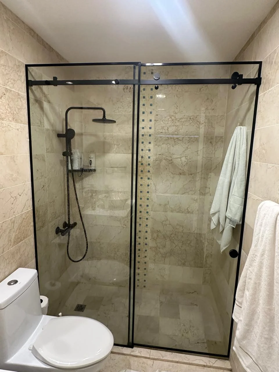 Cabina de baño de vidrio con puerta corredera y perfiles negros